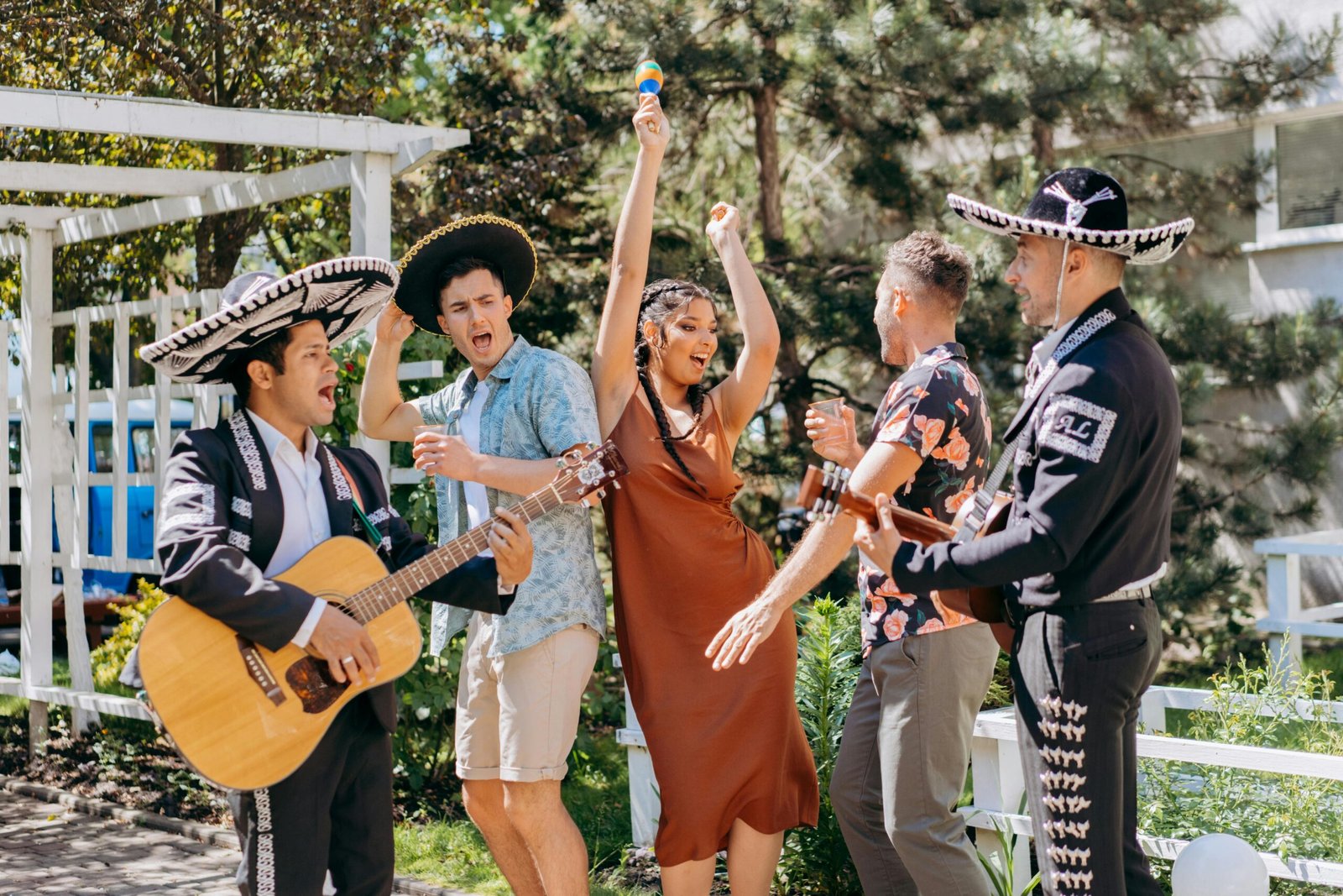 Lively outdoor party with mariachi musicians and people enjoying festive music and dancing.